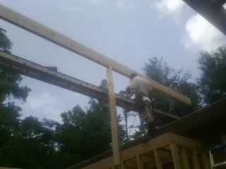 Carpenter setting a ridge beam over a new addition frame — Ice Dam Removal by Roofing Brothers in Starbuck