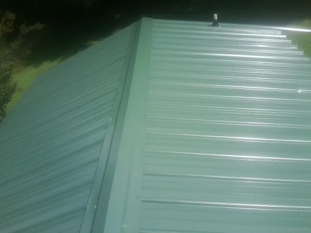New green metal panels meeting at the ridge of a roof — Flat Roof Repair work by our crew in Starbuck