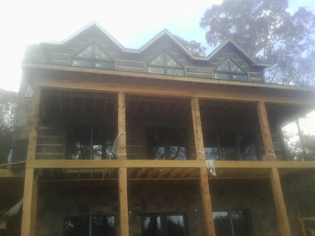 Dormers and porch framing on a large log home under construction — Roof Coating work by our crew in Starbuck