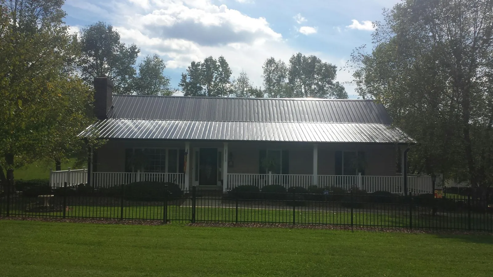 Gray metal roof on a brick ranch with a full width front porch — Gutter Guard Installation work by our crew in Starbuck