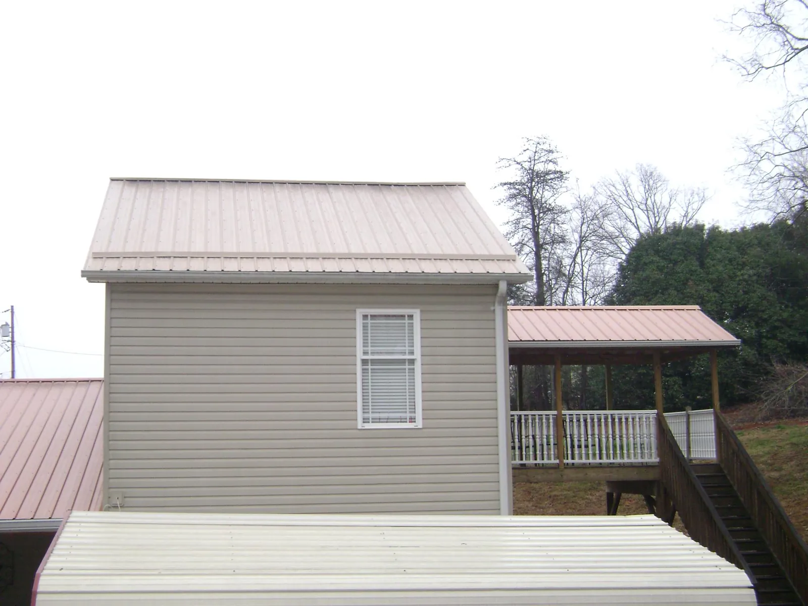 Tan metal roofs on a two story addition and attached porch, from a Roof Replacement job in Starbuck