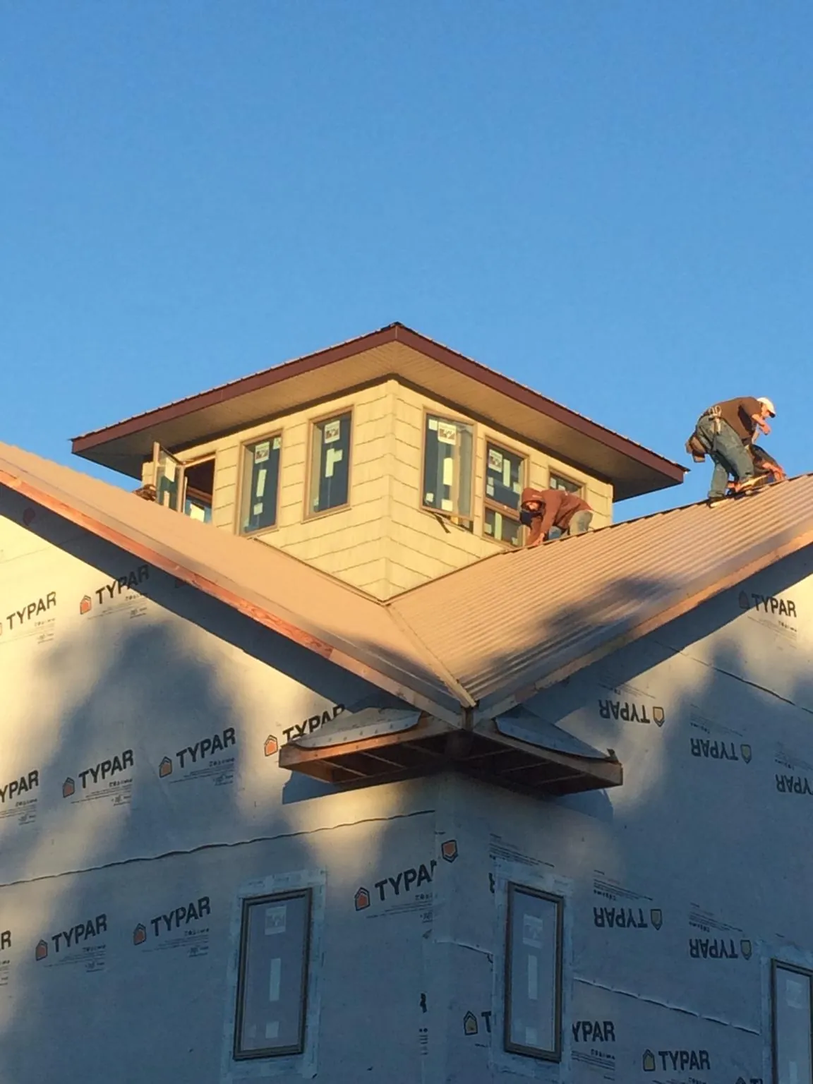 Roofers working around a rooftop cupola on a new metal roof at sunset — Roof Waterproofing in Starbuck by Roofing Brothers